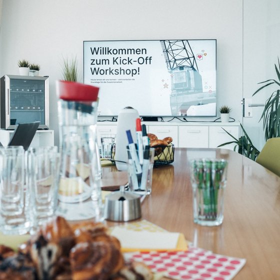 Projekt-Kick-Off Workshop bei cyperfection Meetingraum mit Getränken und Snacks auf dem Tisch, Präsentation auf dem Monitor