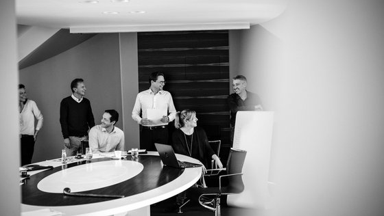 Schwarz-Weiß Fotografie einer Gruppe Personen während eines Meetings