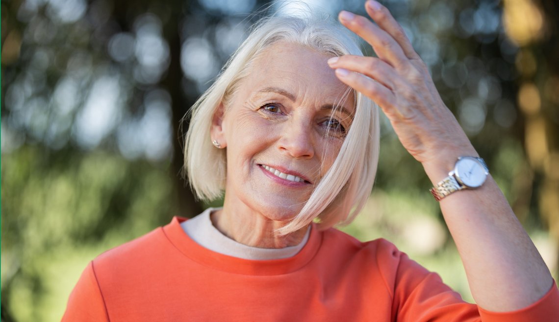 Dame mit orangenem Pulli lächelt in die Kamera