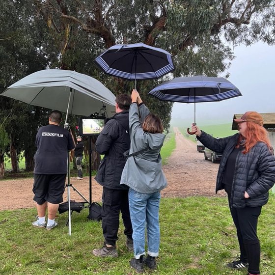 Filmcrew und Personen mit Regenschirmen