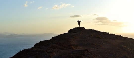 Person auf Berg und Meer im Hintergrund