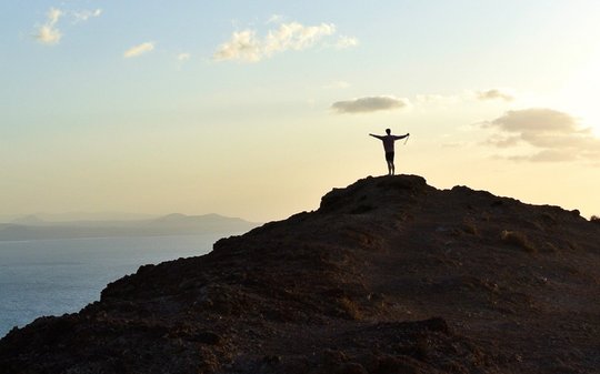 Person auf Berg und Meer im Hintergrund