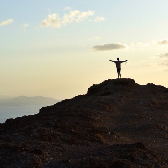 Person auf Berg und Meer im Hintergrund