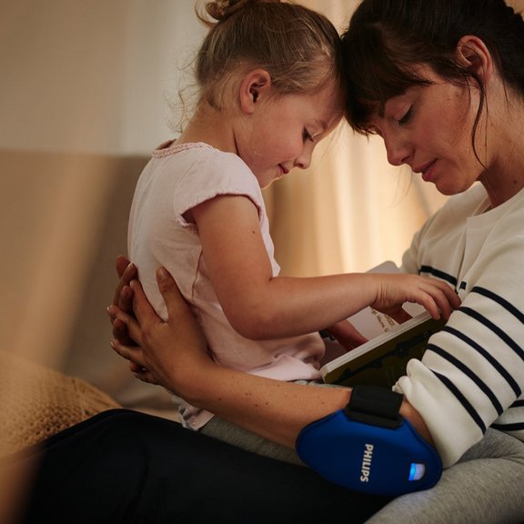 Frau bei der Anwendung von Philips BlueControl mit Kind im Arm