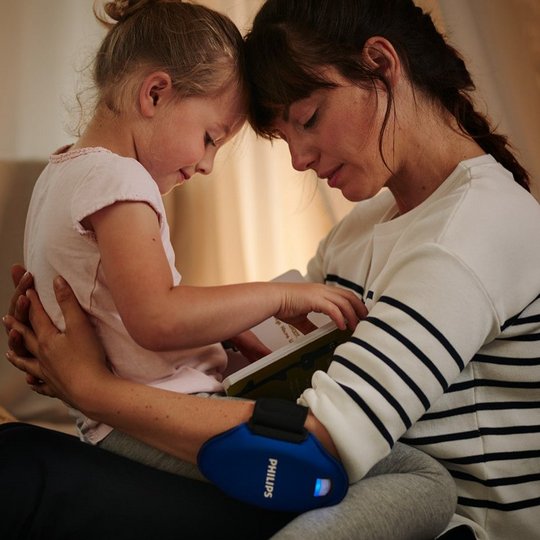 Frau bei der Anwendung von Philips BlueControl mit Kind im Arm